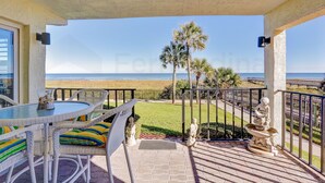 A balcony with a view of the beach, wicker furniture, and a statue. - A1 Amelia South (Fernandina Beach)
