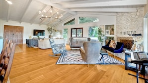 A spacious living room with a high ceiling, wooden flooring, and a large window. - 3046 Skycrest Drive (Fallbrook)