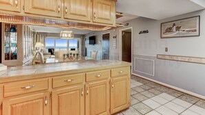 Una cucina con mobili in legno, un piano di lavoro in marmo e un'area pranzo con vista.