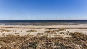 Een strand met duinen en een heldere lucht.