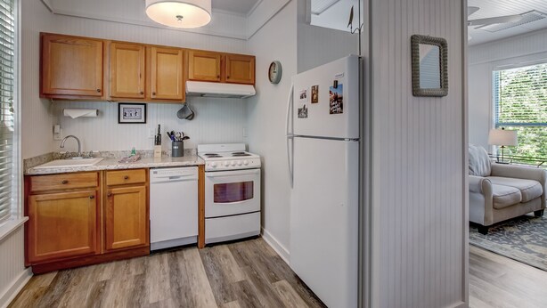 A compact kitchen with wooden cabinets, a white stove, and a refrigerator. - 313 New Street (Fernandina Beach)