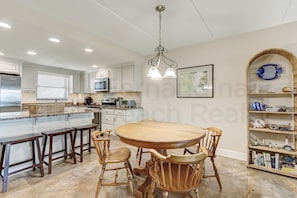 A kitchen with a wooden dining table, white cabinets, and a microwave. - 334 Amelia By The Sea (Fernandina Beach)