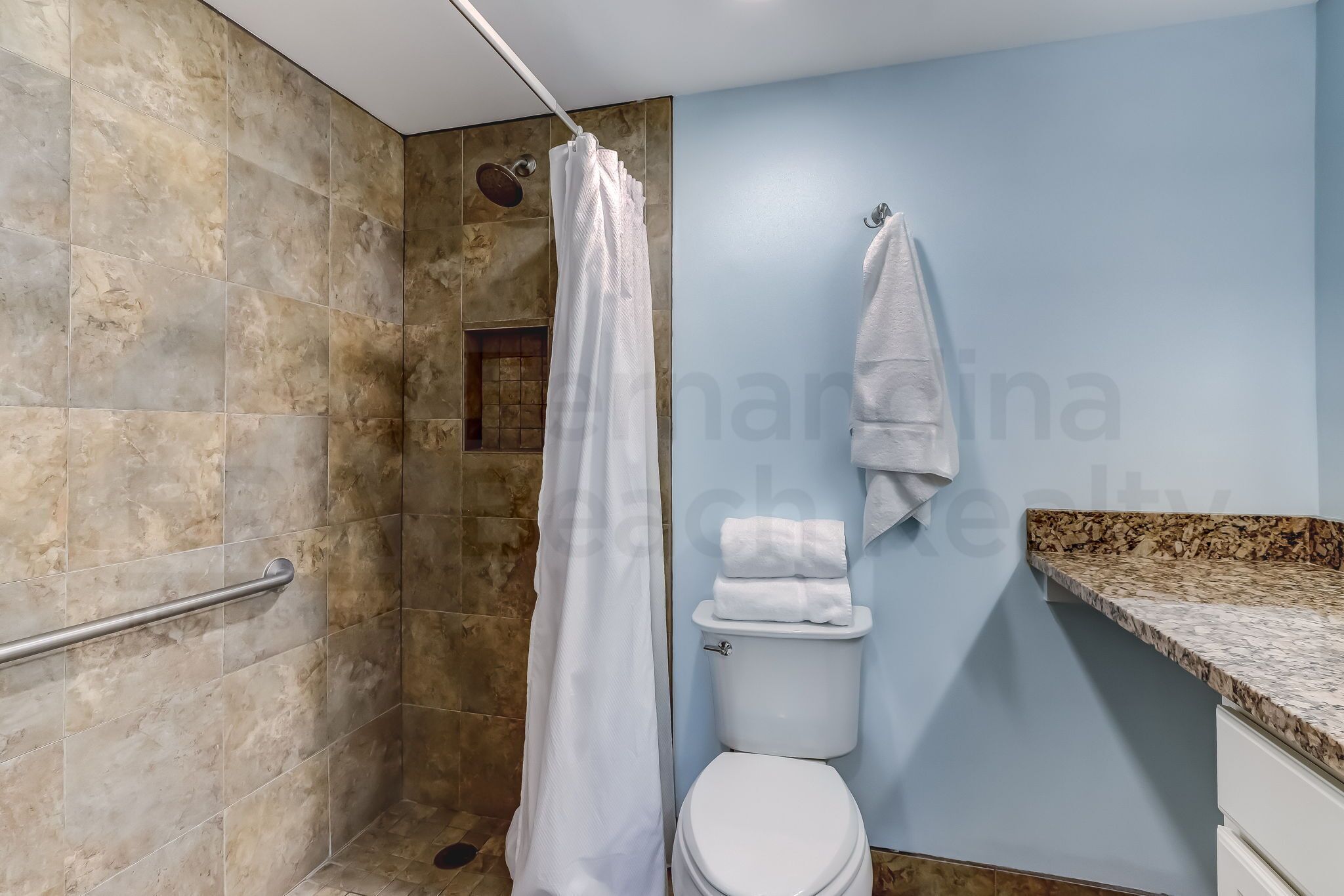 Een badkamer met douche, toilet en handdoekrek.