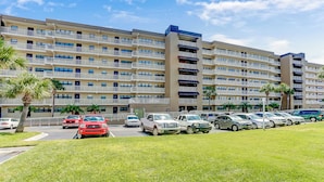 A multi-story hotel with a parking lot and a grassy area in front. - 672 Amelia By The Sea (Fernandina Beach)