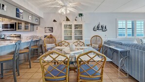 A modern kitchen with a dining area, featuring a central island, built-in appliances, and a ceiling fan. - 672 Amelia By The Sea (Fernandina Beach)