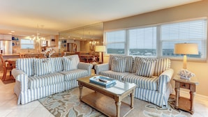 A living room with striped sofas, a glass coffee table, and a side table with a lamp. - 7th Floor, Corner Property on the top Floor With Easy Beach Access Exclusive Fishing Pier (Fernandina Beach)
