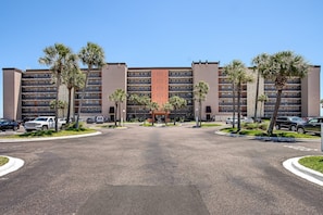 A multi-story hotel with a central entrance, surrounded by palm trees and a parking lot. - B7 Amelia South (Fernandina Beach)