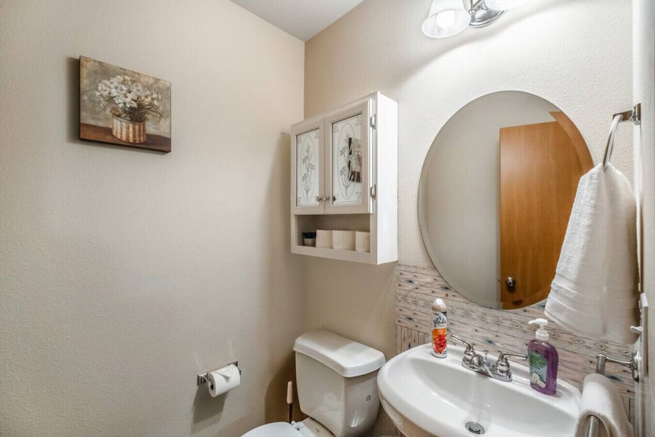 Ein Badezimmer mit Toilette, Waschbecken und einem Schrank mit Pflegeprodukten.