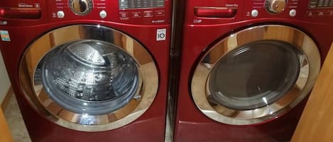 Two red front-loading washing machines with stainless steel doors, control panels, and a "Sensor Dry" label.