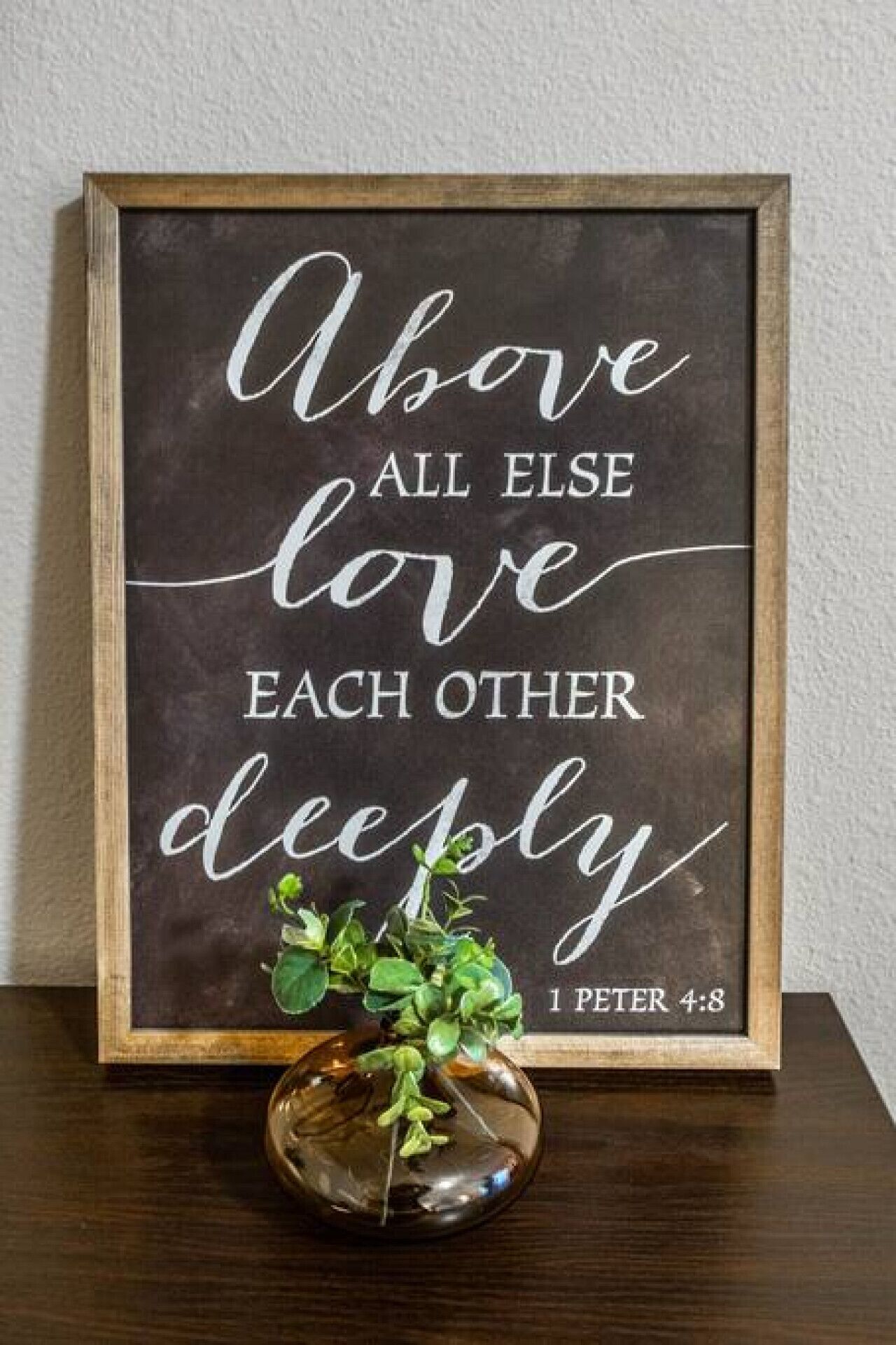 A framed inspirational quote with a small plant in a vase.