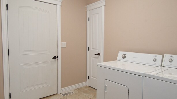 A laundry room with two white doors, a washing machine, and a dryer. - Teton Harmony (Driggs)