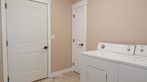 A laundry room with two white doors, a washing machine, and a dryer. - Teton Harmony (Driggs)