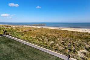 Une vue sur la côte, avec une plage, une jetée et une zone herbeuse délimitée par une clôture.