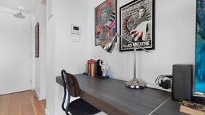 Un intérieur moderne avec un bureau, une chaise, des affiches et un ordinateur.
