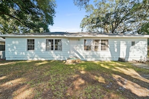 A single-story house with a front porch, a small front yard, and a garage. - Little Beach House (Fort Walton Beach)