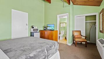 A bedroom with a bed, a wooden dresser, a television, and a chair.
