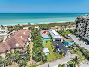 A coastal hotel with a parking lot, a building with a blue roof, and a view of the beach. - Ocean Drive Villas- Unit A (Fort Pierce)
