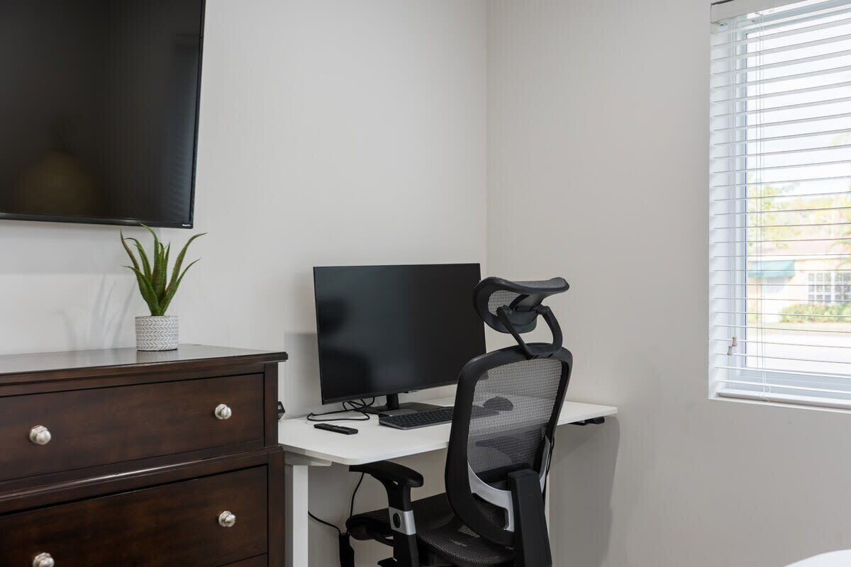 Un espacio de oficina moderno con un escritorio, computadora, silla y una planta en maceta.