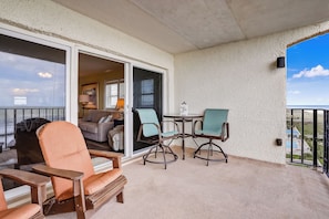 Ein Balkon mit Tisch, Stühlen, einer Sitzecke und einer Glastür zu einem Innenraum.