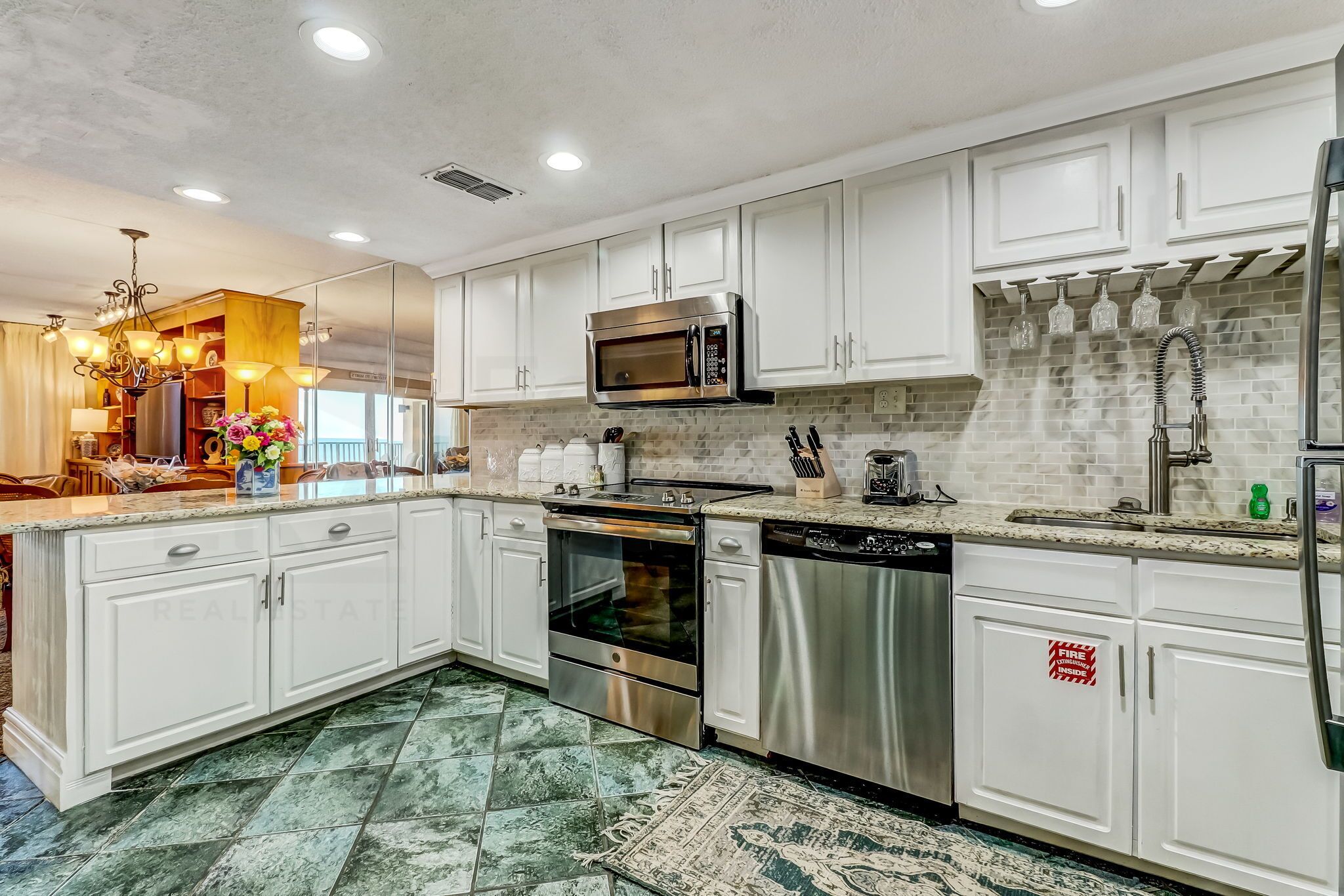A modern kitchen with white cabinets, stainless steel appliances, and a patterned backsplash.
