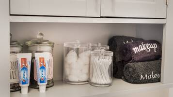 A shelf with jars of cotton balls, cotton swabs, and Crest toothpaste.