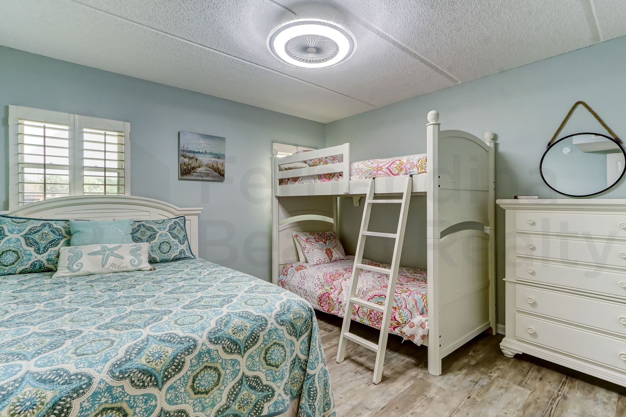 A bedroom with a bunk bed, a dresser, and a window with blinds.