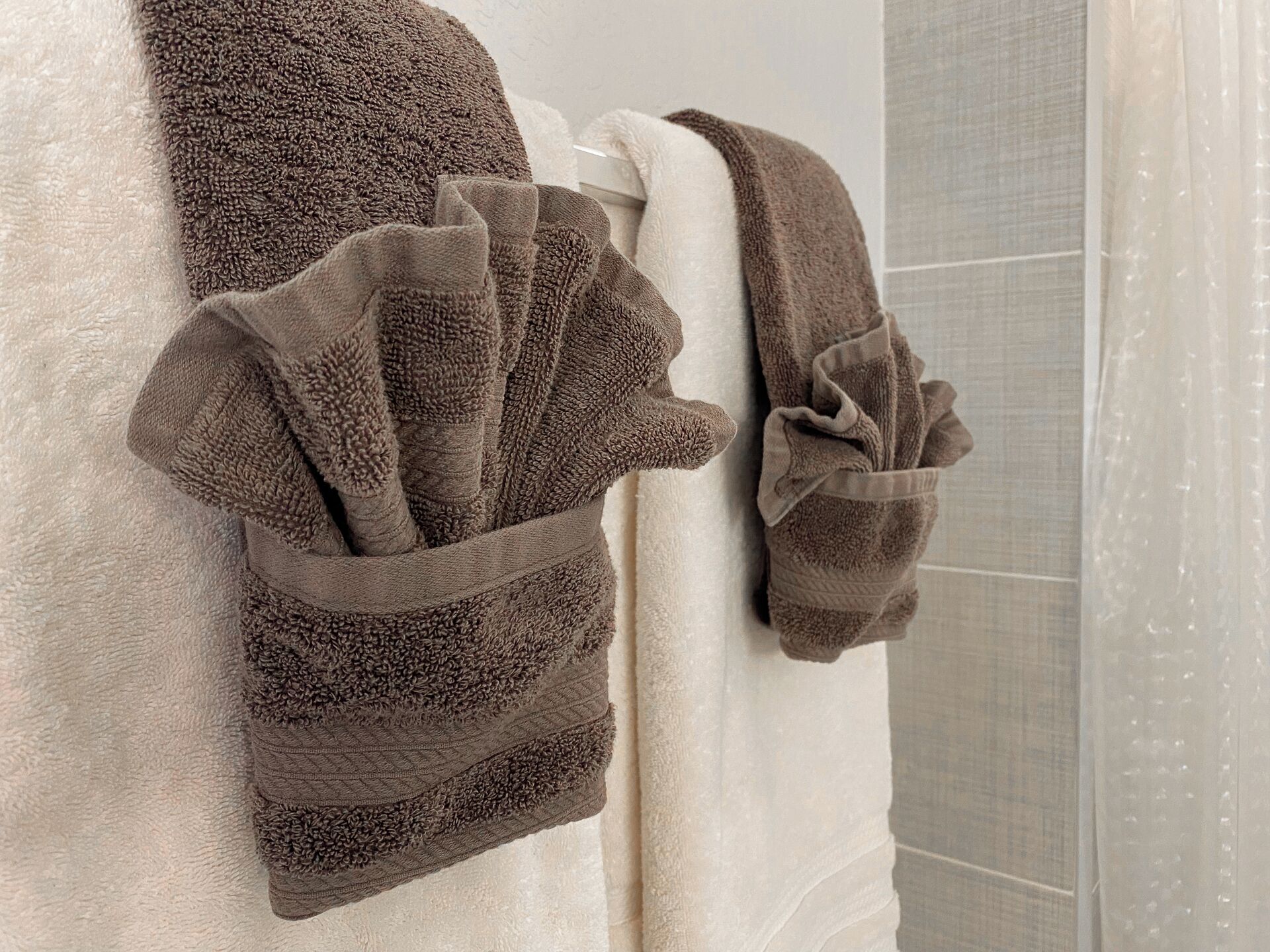 Een badkamer met een witte badkuip, een bruine handdoek en een witte douchegordijn.