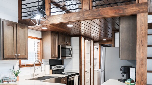 Een moderne keuken met houten kastjes, een centraal eiland en een inbouwmagnetron.