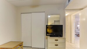 A bedroom with a bed, a television on a dresser, a wardrobe, and a small table. - J1 Amelia South (Fernandina Beach)
