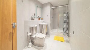 Un bagno moderno con toilette, lavandino e doccia.