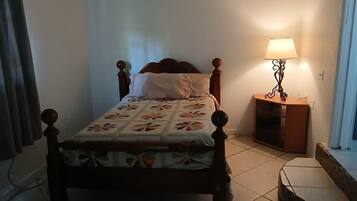 A single bed with a floral bedspread, a wooden headboard, and a nightstand with a lamp.