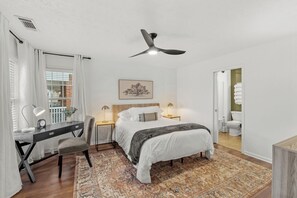Ein Schlafzimmer mit Bett, Schreibtisch, Stuhl und Deckenventilator.