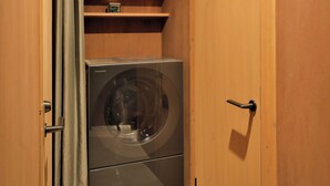 A compact room with a washing machine, wooden cabinets, and a small shelf. - Nozomu House02 (Kyoto)