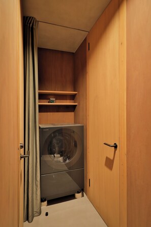 A compact room with a washing machine, wooden cabinets, and a small shelf. - Nozomu House02 (Kyoto)