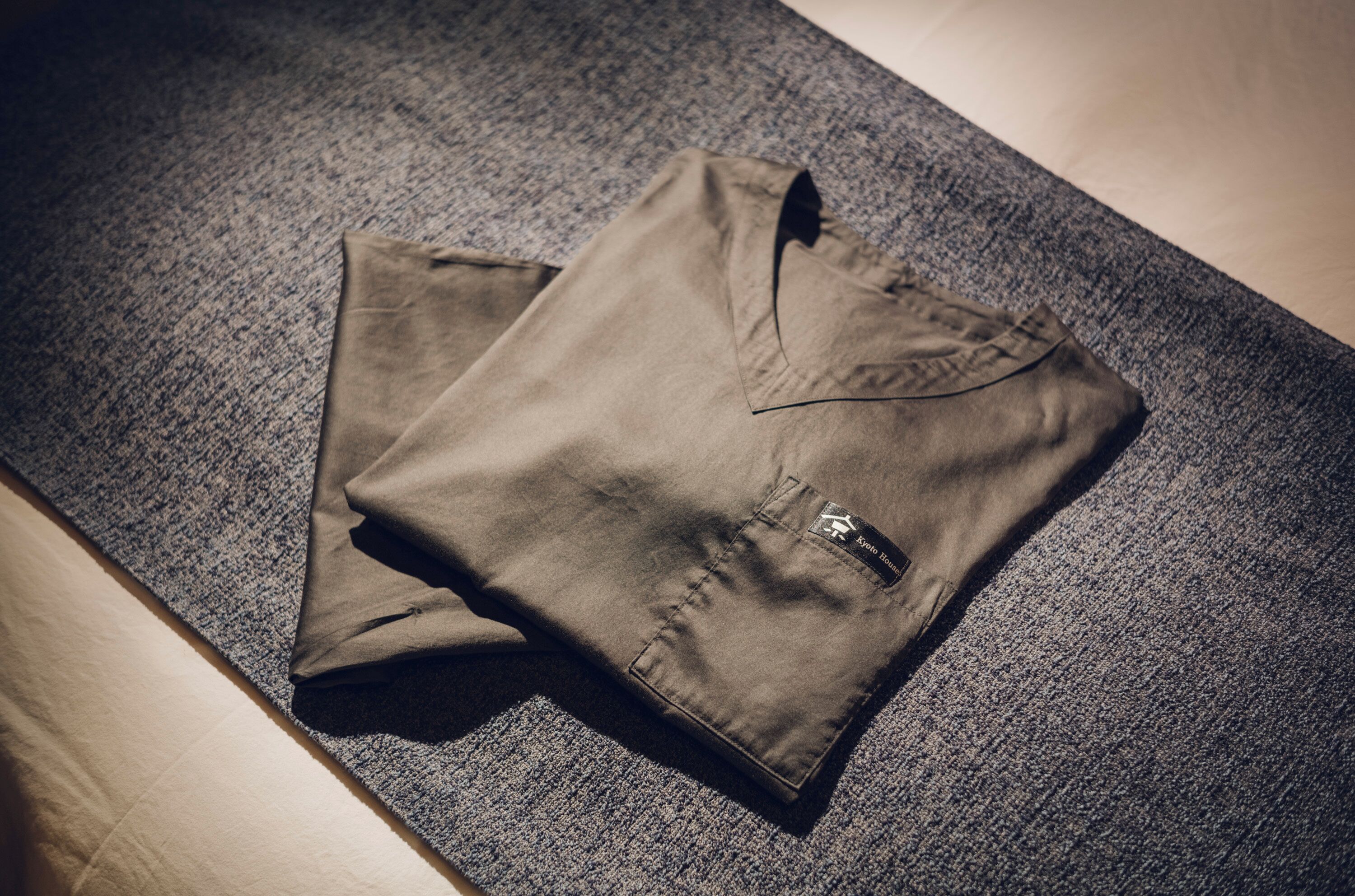 A pair of folded trousers on a textured grey carpet.