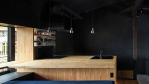 Een moderne keuken met een houten aanrecht, zwarte kastjes en een zwarte spoelbak.