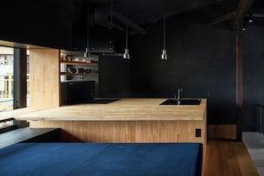 Une cuisine moderne avec un plan de travail en bois, des meubles de couleur noire et un évier noir.