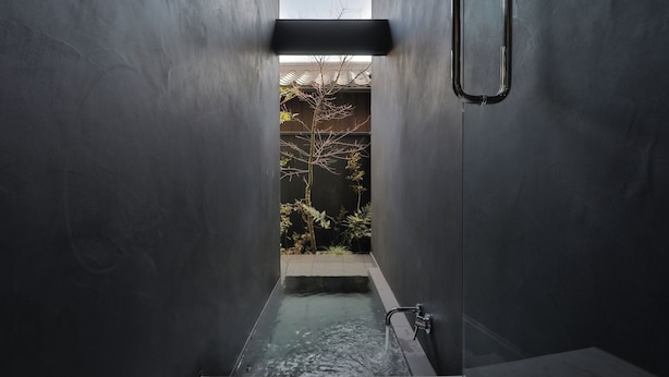 A narrow, modern bathroom with a built-in bathtub, a visible water spout, and a small window at the top. - Nozomu House02 (Kyoto)