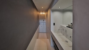A modern bathroom with a long, narrow design, a large mirror, and a walk-in shower. - Nozomu House02 (Kyoto)