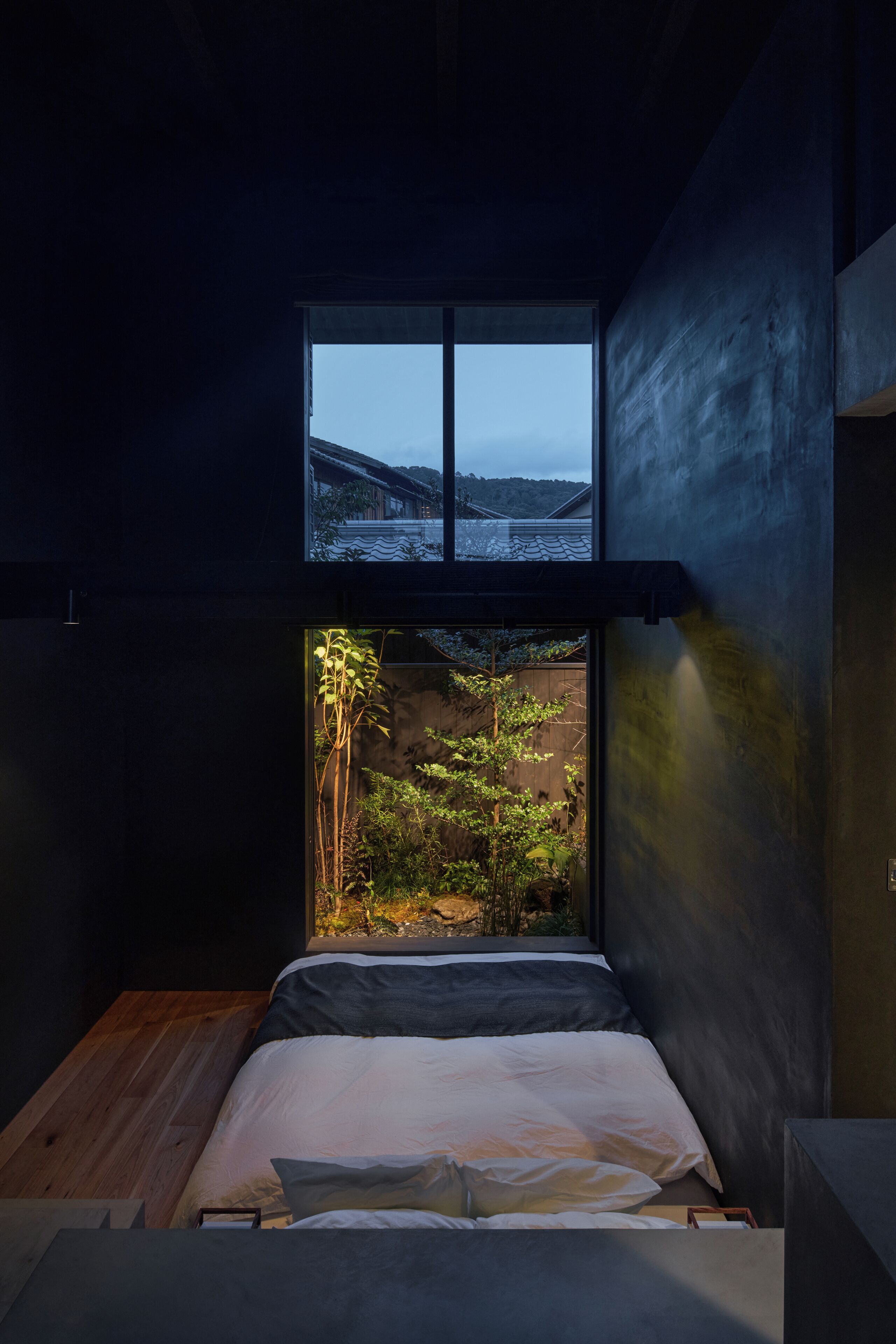 A bedroom with a bed, a window, and a view of a garden.