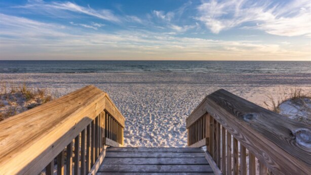 Un muelle de madera que conduce a una playa con cielo despejado.