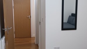 A hallway with wooden flooring, white walls, and a door leading to another room. - Cosy Central Cardiff Retreat (Cardiff)