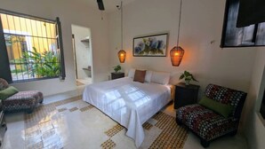 A bedroom with a bed, a chair, a ceiling fan, and a window with a view of greenery. - Casa Kaax - by Kanaa (Mérida)