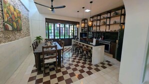 A spacious kitchen with a checkered floor, a dining area with wooden furniture, and a ceiling fan. - Casa Kaax - by Kanaa (Mérida)