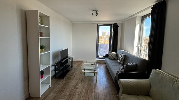 A modern living room with a sofa, TV, and built-in shelving. - 4 Bed 2 Bath Balcony Retreat - 15min-O2 Arena! (London)