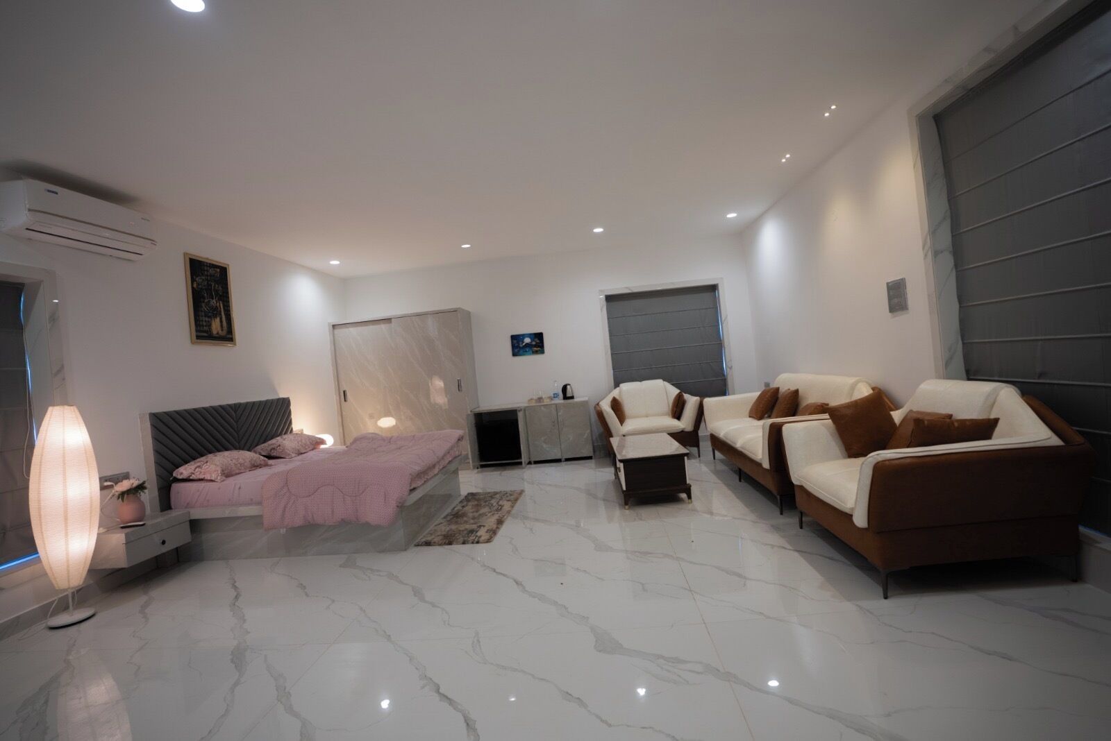 Quarto moderno com cama, escrivaninha, guarda-roupa e dois sofás.