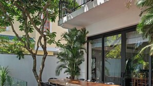An outdoor dining area with a wooden table and chairs, surrounded by potted plants and trees. - Sila Ananda 6BRs Pool Villa Dao Xanh Island Da Nang (Da Nang)
