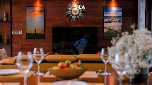A dining area with a wooden wall, a fireplace, and a logo above it. - Sila Ananda 6BRs Pool Villa Dao Xanh Island Da Nang (Da Nang)