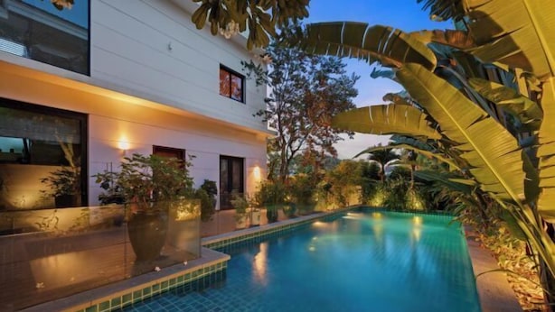 A modern building with a swimming pool surrounded by tropical plants. - Sila Ananda 6BRs Pool Villa Dao Xanh Island Da Nang (Da Nang)