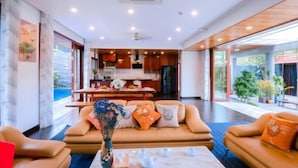 A modern living room with a sofa set, a coffee table with teapots, and a vase of flowers. - Sila Ananda 6BRs Pool Villa Dao Xanh Island Da Nang (Da Nang)